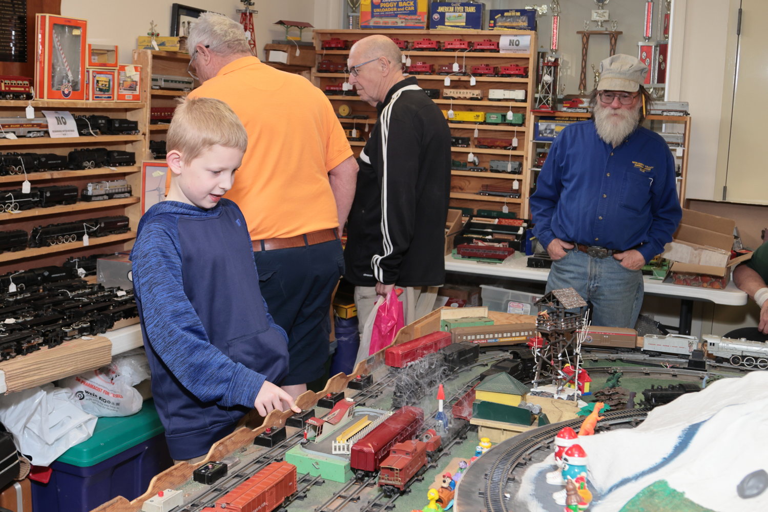 Pamela Pearl brought her son Maxwell to the Model Train Show and Sale from Greeley, PA. A first-time visitor, Maxwell was having fun pressing buttons to control different elements on the train layout.  The man on the right in the blue shirt is Tom Keegan, one of the owners of the trains and layout.